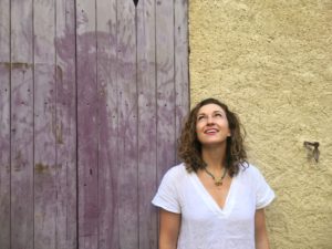 Lauren in Moustiers-Sainte-Marie, Provence, in white linen dress in front of purple door