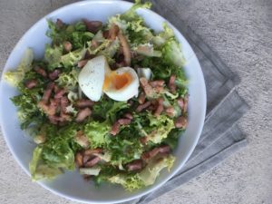 Salade Lyonnaise (frisée, lardons, and egg) on a linen napkin