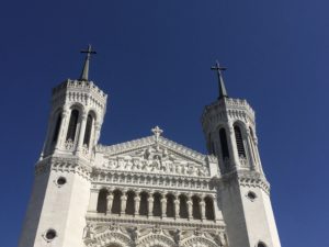 The facade of Notre Dame du Fourviere against a bright blue sky in Lyon, France