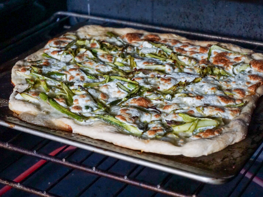 Homemade asparagus pizza with mozzarella in oven