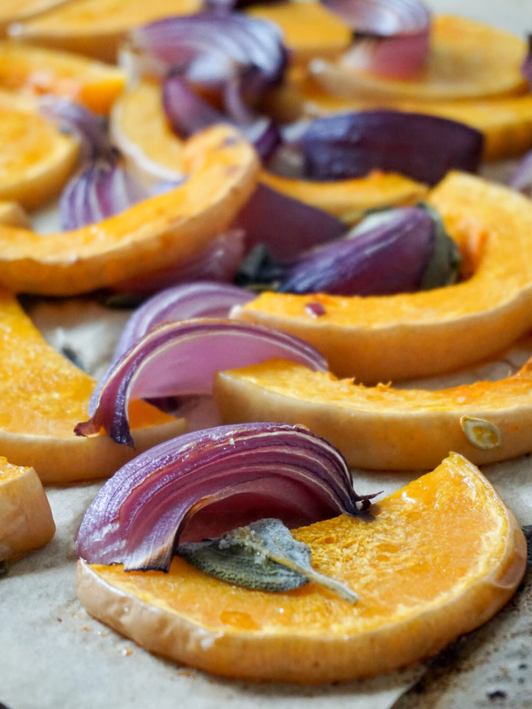 Roasted butternut squash, onions, and sage on baking pan for Ottolenghi recipe