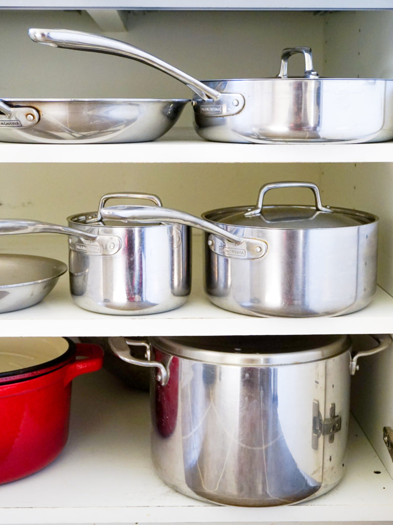 Five stainless steel Tramontina pots and pans in cupboard