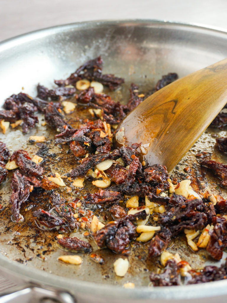 Sun-dried tomatoes, garlic, and red pepper flakes frying in bacon fat