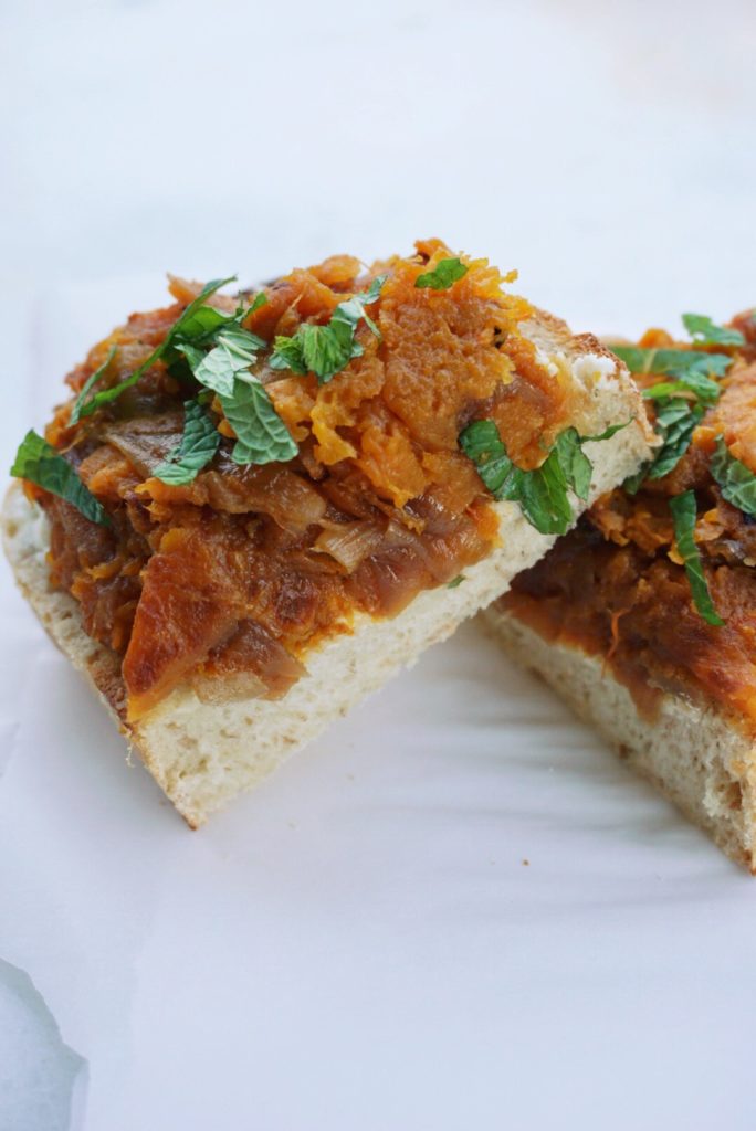 Squash toasts with goat's cheese and caramelized onions, sliced in half