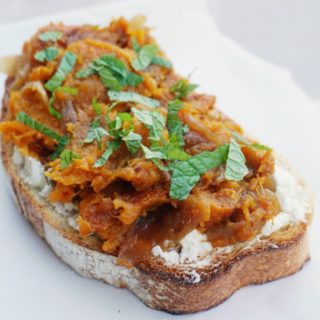 Squash toasts with goat's cheese and caramelized onions on white background