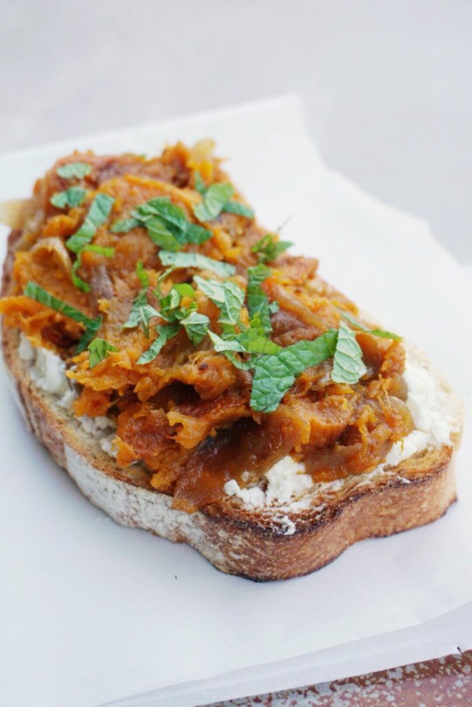 Squash toasts with goat's cheese and caramelized onions on white background