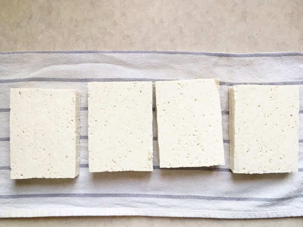 Tofu on white and blue striped towel on counter, ready to be pressed