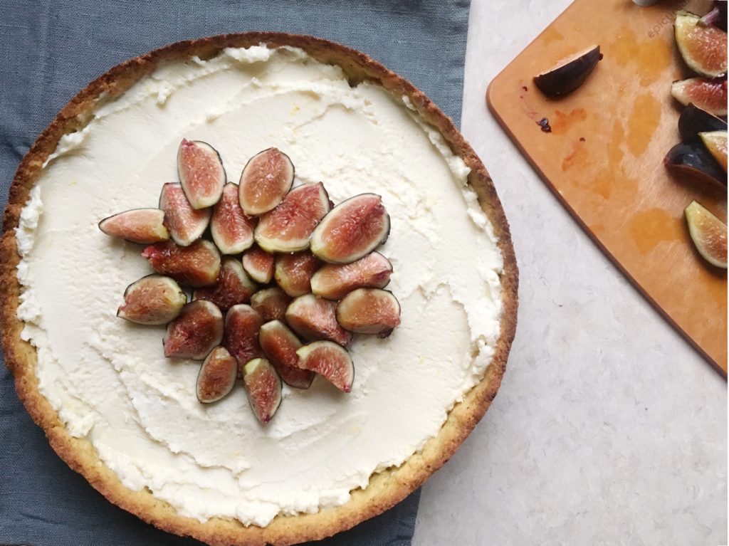 Fig tart with grey linen background and cutting board