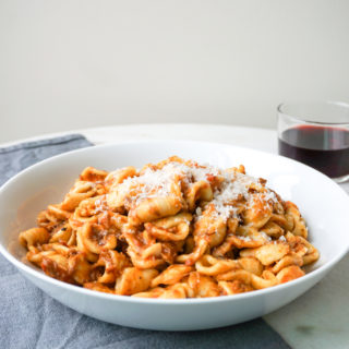 A pork, lamb, and beef meat and tomato ragu over orecchiette pasta