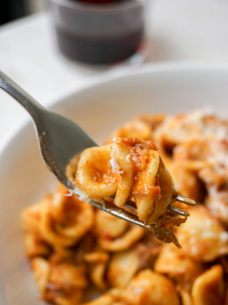 Forkful of lamb, beef, and pork ragu on orecchiette pasta