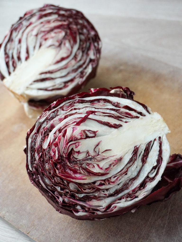 Halved radicchio on cutting board for farro salad with roasted root vegetables and pomegranate