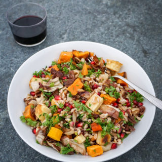 Farro Salad with Radicchio, Root Vegetables, and Pomegranate with glass of wine on grey background