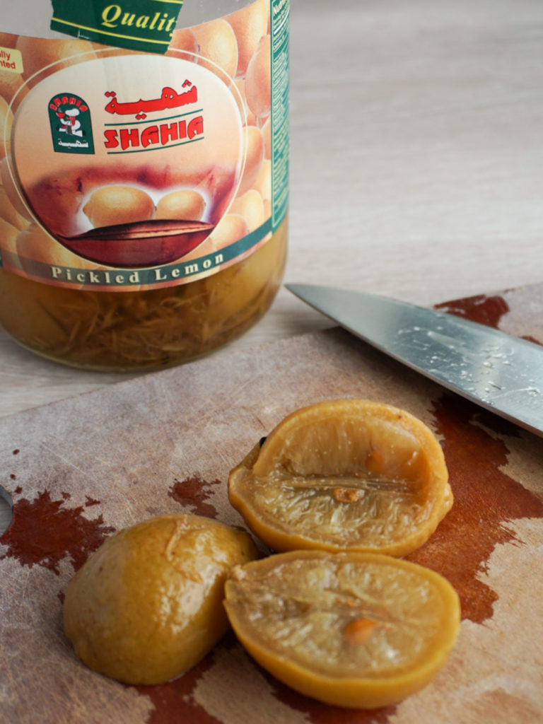 Preserved lemons on cutting board with jar in background