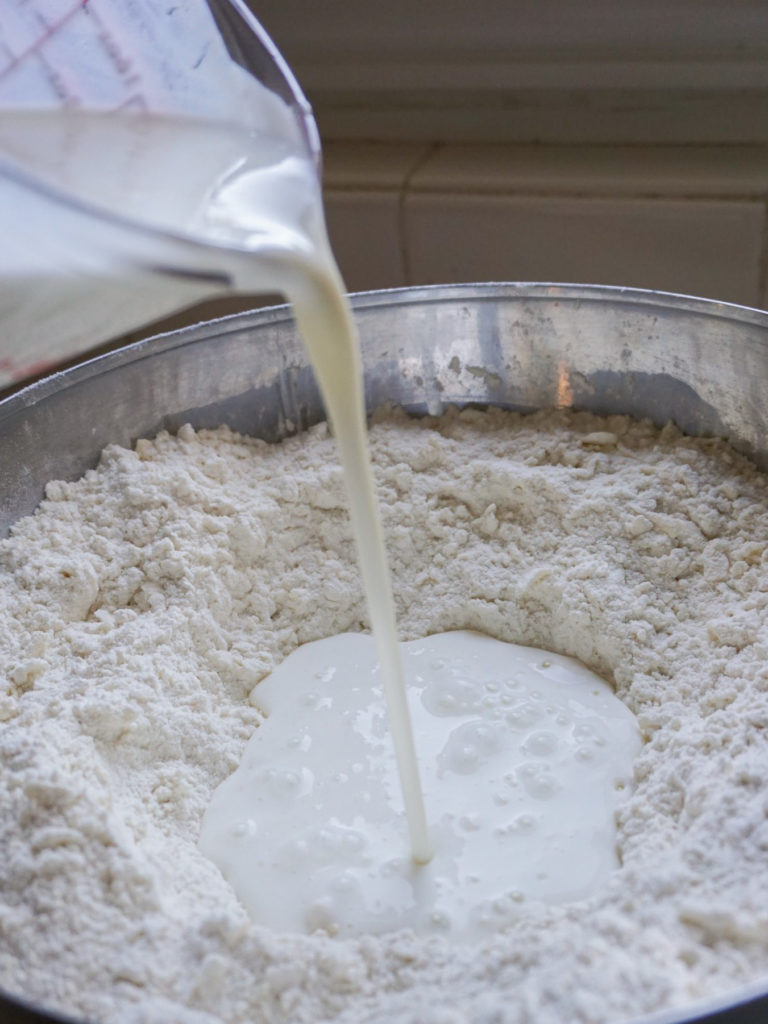 Pouring milk into flour for British-style scones