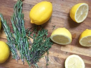 rosemary, thyme, and lemons on wooden chopping block