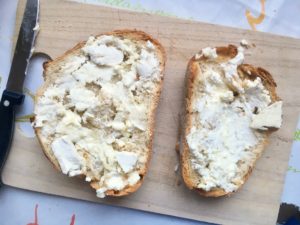 slices of bread, toasted, with goat cheese, rustic on cutting board