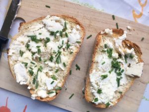 slices of bread, toasted, with goat cheese and chives, rustic on cutting board