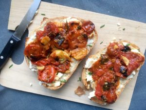 toasts with goat cheese, chives, and herbed cherry tomato compote rustic on cutting board a la david lebovitz