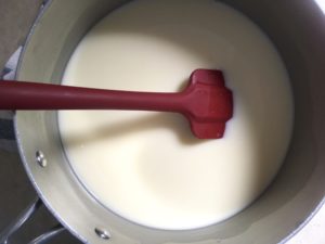 heating cream in pot with red spatula
