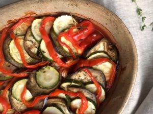 Provençale ratatouille in gratin dish, on linen tablecloth with thyme scattered alongside