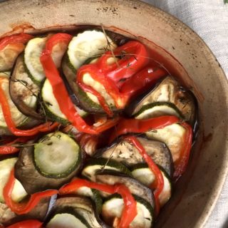 Provençale ratatouille in gratin dish, on linen tablecloth with thyme scattered alongside