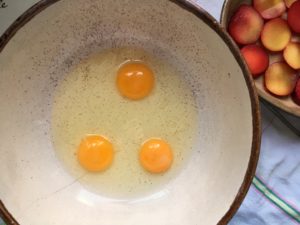 Three golden egg yolks in rustic ceramic bowl