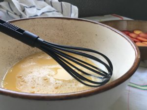 whisk in ceramic bowl with eggs and milk
