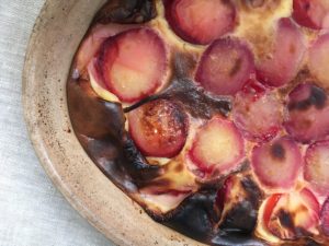 Plum clafoutis in rustic brown French gratin dish