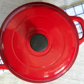 Red Tramontana 6.5 quart Dutch oven on checkered dishtowel and linen tablecloth