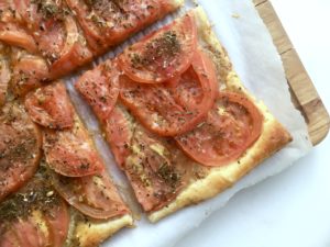 Tomato tart with dijon and herbes de provence on cutting board