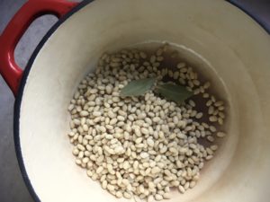 White beans and bay leaves in red dutch oven