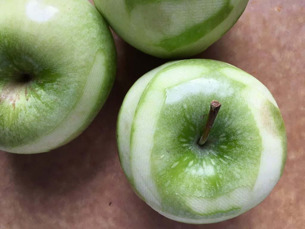 roughly peeled granny smith apples on epicurean cutting board