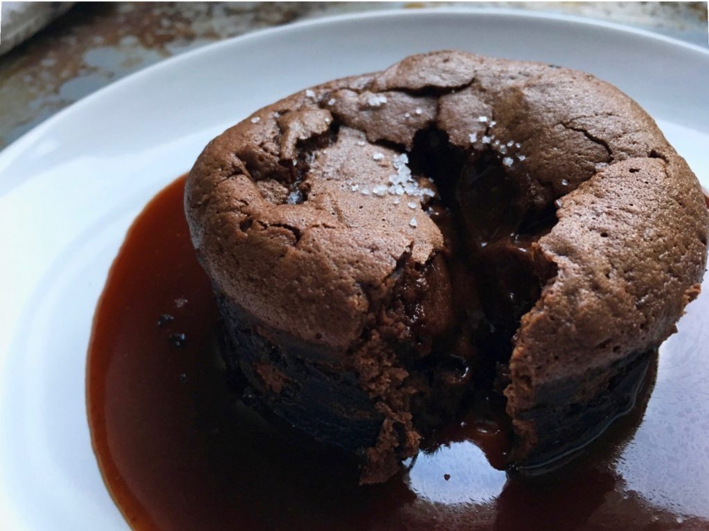 David Lebovitz warm chocolate cake, on a plate surrounded by salted butter caramel sauce