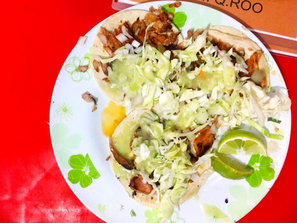 Al pastor tacos on a white plate and red table at Antojitos La Chiapaneca in Tulum