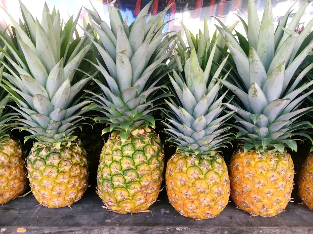 Four pineapples on a shelf in the market in Tulum