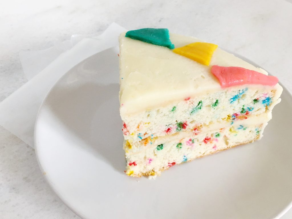 Slice of homemade funfetti birthday cake on white plate