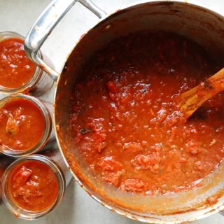 Bold marinara sauce in pot and in six canning jars