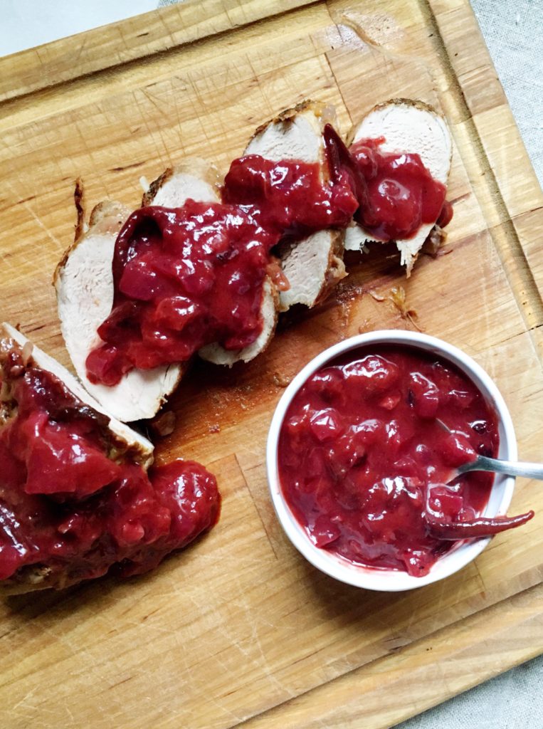 Pork tenderloin with plum barbecue sauce on wood carving board