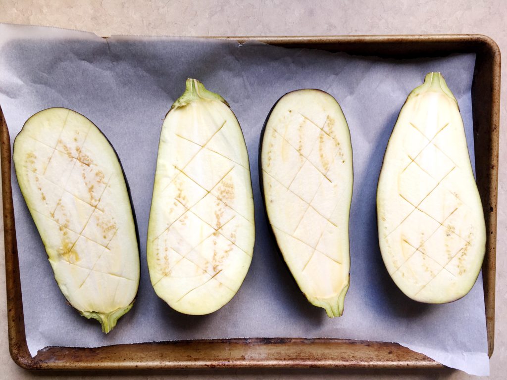 Two eggplants, halved and scored on rimmed baking pan