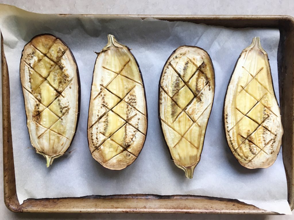 Two eggplants, halved, scored, and baked on rimmed baking sheet