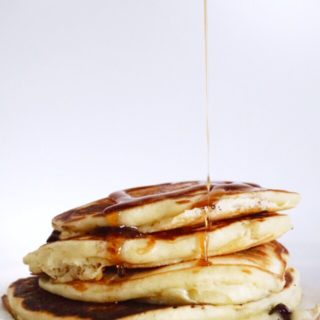 A stack of four Bette's Pancakes with a drizzle of maple syrup