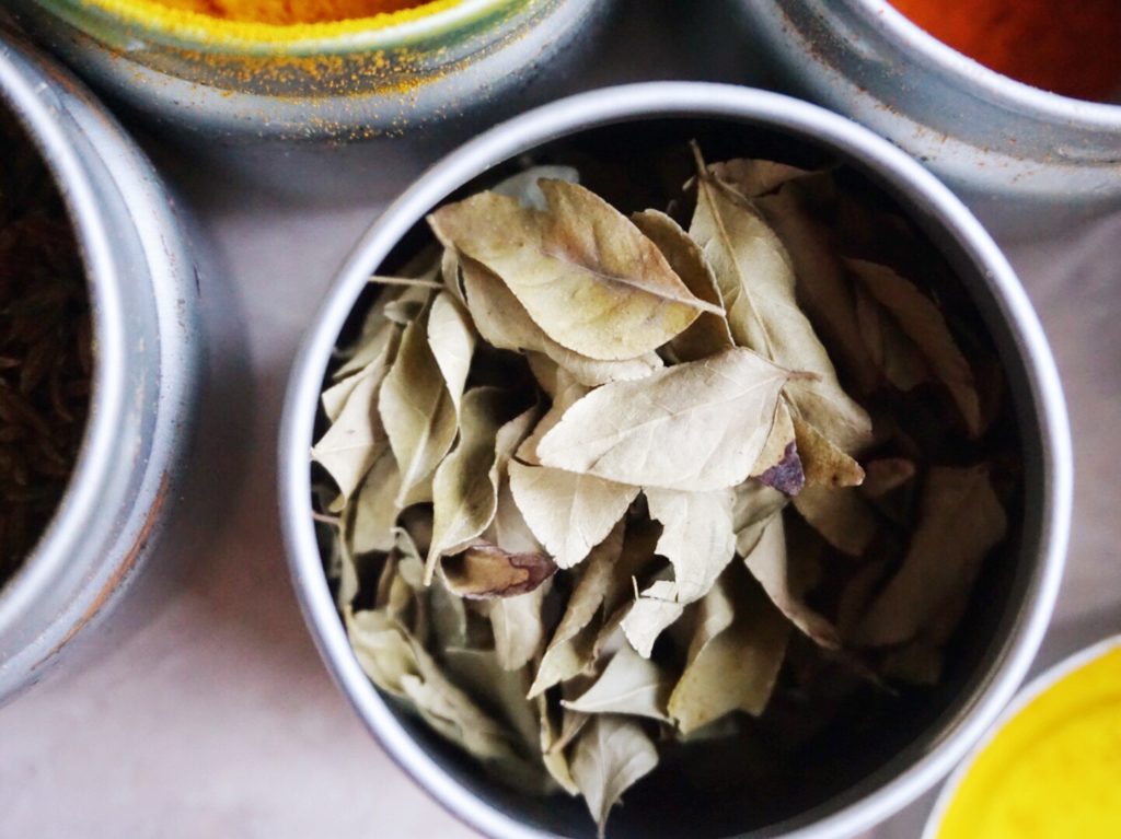 Curry leaves in steel spice tin