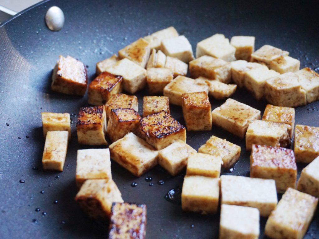 Tofu cubes frying in pan