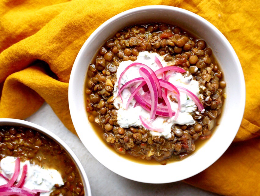 One bowl of Slow Cooker Dal with Quick-Pickled Onions and Cilantro-Yogurt Dollop on yellow linen background