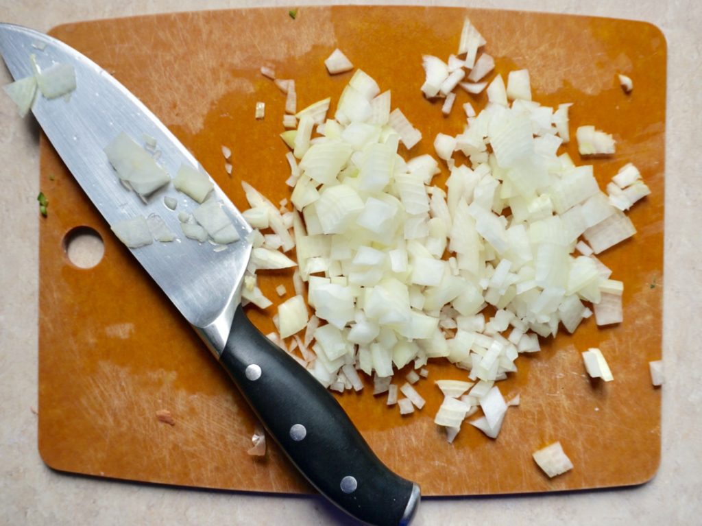 Chopped onion on cutting board with knife for Slow Cooker Dal with Quick-Pickled Onions and Cilantro-Yogurt Dollop