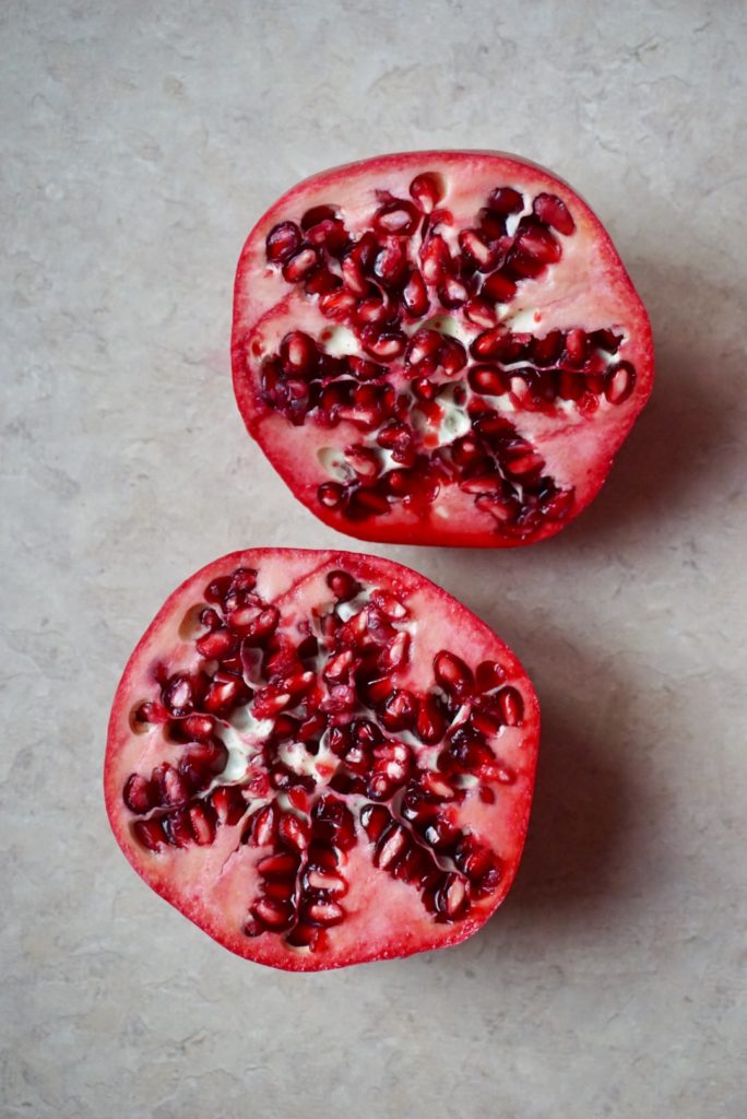 Halved pomegranate for Brussels sprouts, apple, and pomegranate salad