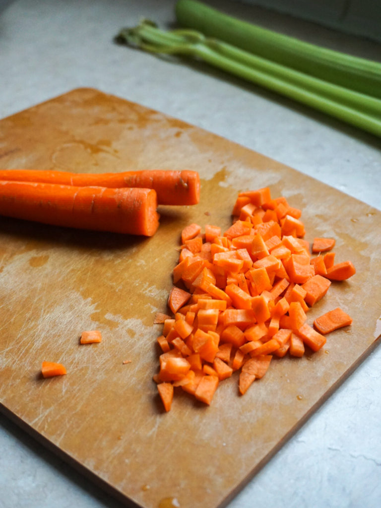 Diced carrots on epicurean cutting board for French Lentil Salad with Goat Cheese and Walnuts