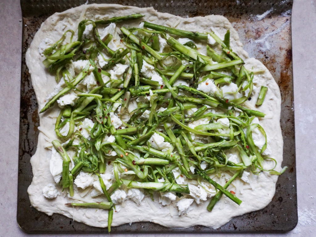 Amoeba-shaped homemade asparagus pizza with mozzarella