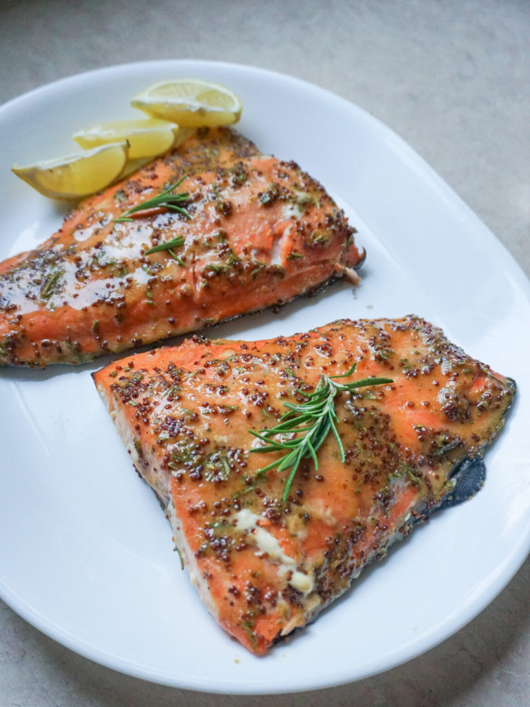 Wild caught salmon marinaded with mustard, rosemary, and honey on white plate