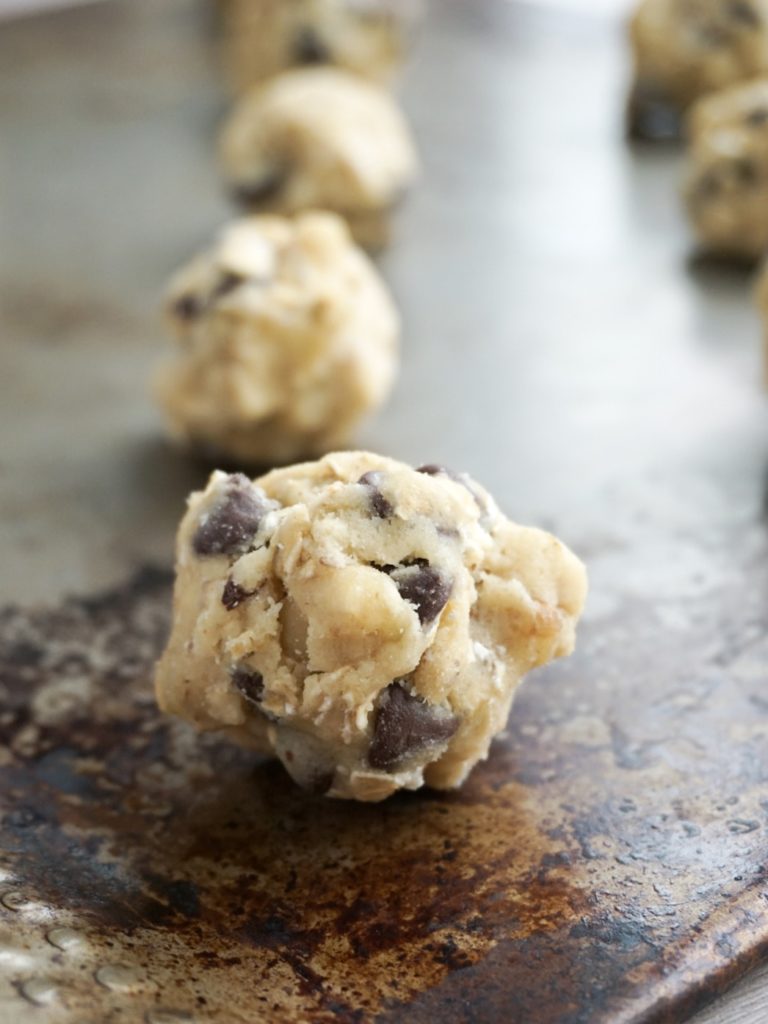Raw cookie dough balls for mom's oatmeal chocolate chip cookies, on baking sheet